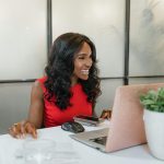 smiling woman in a red dress, using a laptop