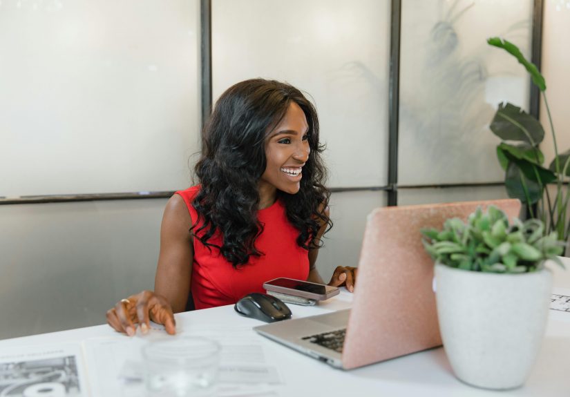 smiling woman in a red dress, using a laptop
