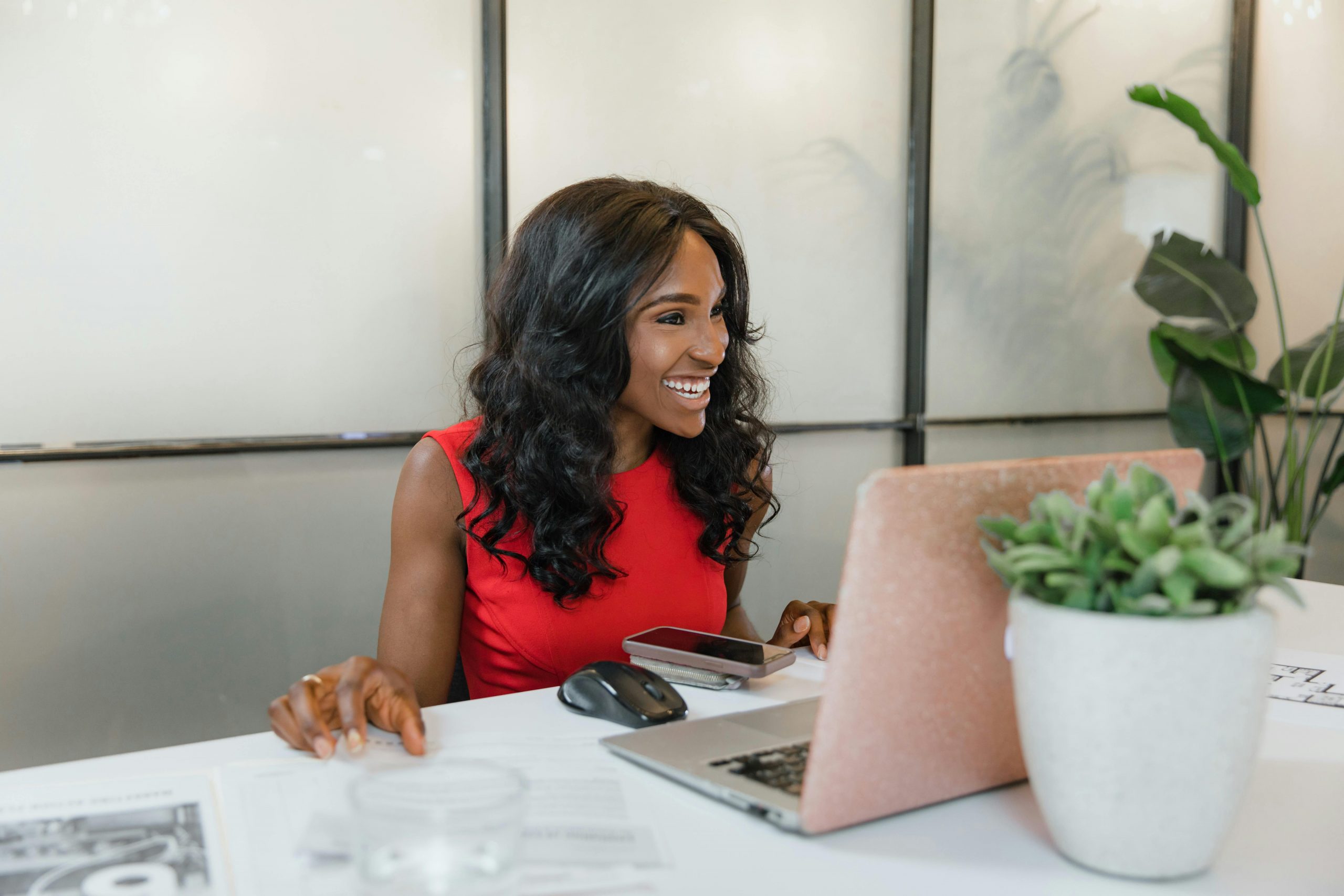 smiling woman in a red dress, using a laptop