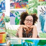 smiling woman selling artworks at an outdoor market