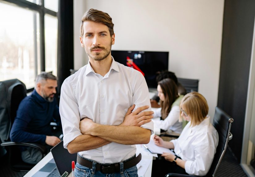 man standing in a conference room, with his colleagues sitting behind him
