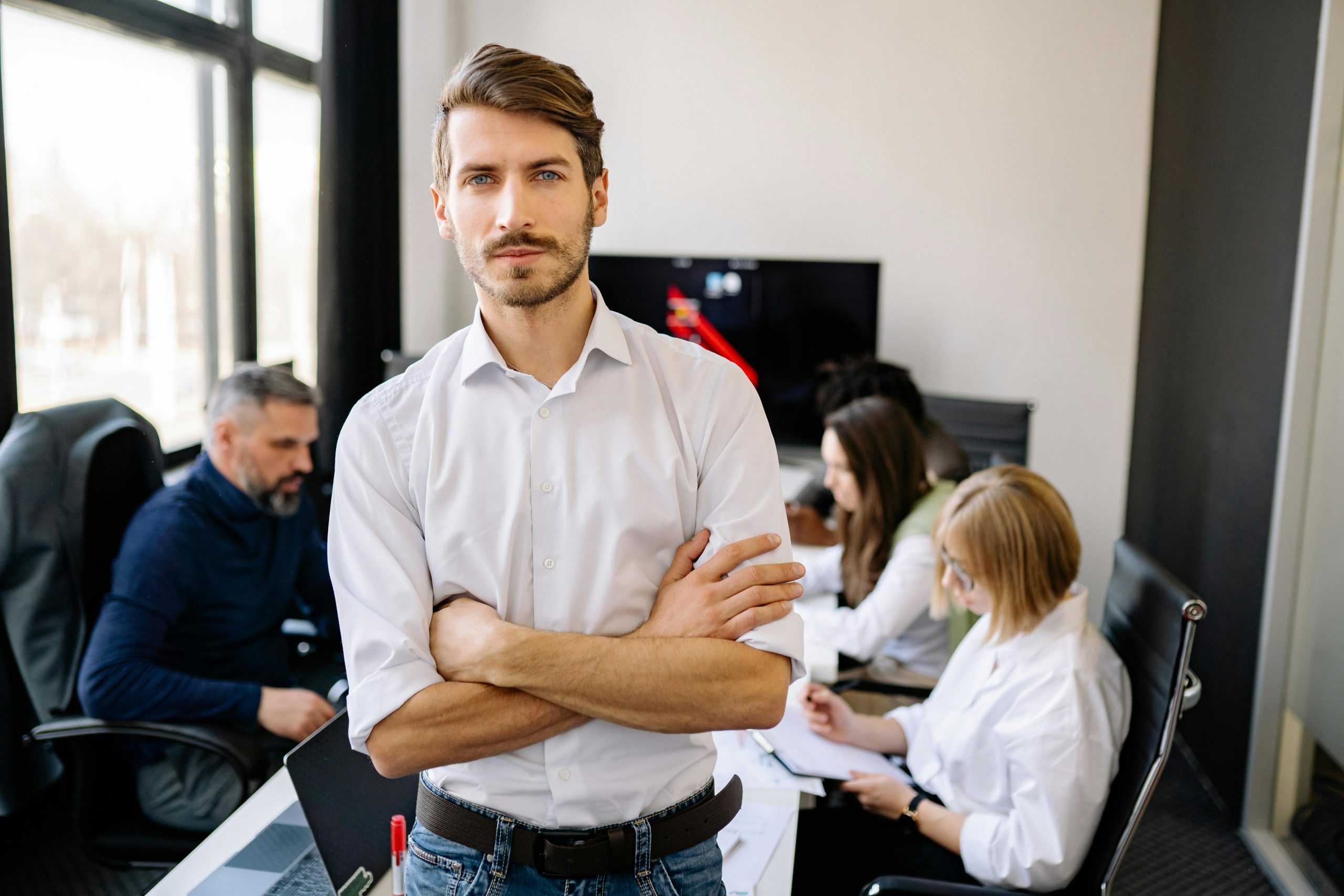 man standing in a conference room, with his colleagues sitting behind him